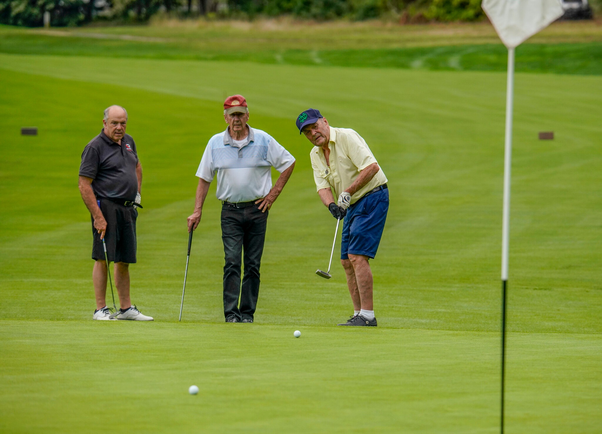 Three men playing on the green.